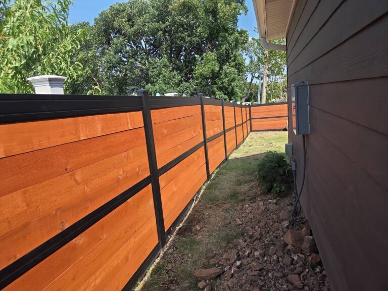 Horizontal cedar fence with black frame lining a narrow side yard beside a house